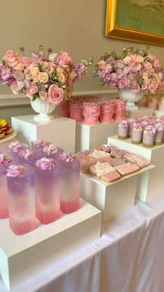 there are many desserts on the table with pink and purple frosted treats in vases