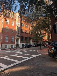 an empty street with cars parked on both sides and buildings in the backround