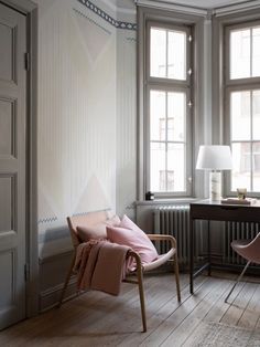 two chairs and a desk in a room with windows on both sides of the wall