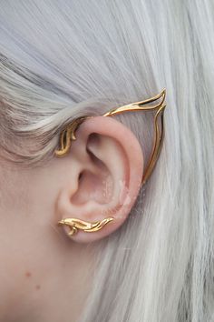 a woman with white hair wearing gold ear cuffs