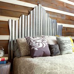 a bed with lots of pillows on it in front of a wooden paneled wall