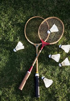 badminton rackets and shuttles laid out on the grass in front of each other