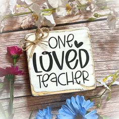 a sign that says one loved teacher next to some flowers