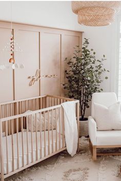 a baby's room with a crib, rocking chair and potted plant