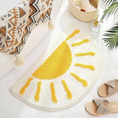 a yellow and white rug sitting on top of a table next to sandals, potted plant