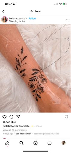 a tattoo on someone's arm that has black flowers and leaves on it,