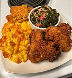 fried chicken and macaroni and cheese on a white plate with a side dish