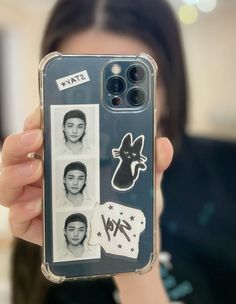 a person holding up a cell phone case with stickers on it