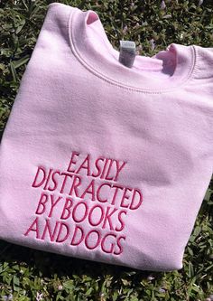 Cuddle up with your favorite book and cozy into our Distracted By Books And Dogs Sweater - where literary passion meets ultimate comfort. The perfect book lover gift or for just yourself! ✨ Embroidered Clothes Ideas, Sweatshirts Ideas, Custom Embroidered Sweatshirt, Book Lover Gifts, Book Clothes, Embroidered Crewneck, Embroidered Clothes, Embroidered Sweater, Embroidered Sweatshirt