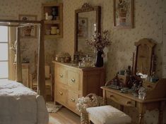 an old fashioned bedroom with floral wallpaper and antique furniture, including a dressing table