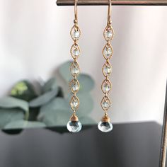 "These Blue Topaz teardrops perfectly capture the clarity of an early morning mist on the Sea. In some light they appear almost clear and in other, have a piercing gray/blue. Both the faceted central stone of the drop and the faceted smaller Rondelles have been handpicked and matched for their clarity and tone. Each round link, in either 14K Gold Fill or Sterling Silver, has one of these Topaz Rondelles nestled in its embrace. Balanced against these links is the Blue Topaz tear drop at its base. Elegant Teardrop Crystal Gemstone Earrings, Elegant Teardrop Plug Earrings With Ear Wire, Elegant Pierced Briolette Earrings, Elegant Briolette Crystal Earrings Gift, Elegant Gemstone Linear Dangle Earrings, Elegant Gemstone Dangle Linear Earrings, Elegant Dangle Linear Earrings With Gemstones, Elegant Gemstone Chandelier Earrings With Long Drop, Elegant Long Drop Gemstone Chandelier Earrings