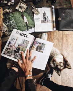 a person is reading a book with their dog on the floor next to them and other items