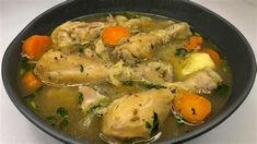 a bowl filled with chicken and carrots on top of a table