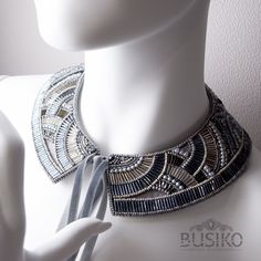 a white mannequin wearing a silver and black necklace