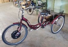 a red bicycle parked in a garage next to two bicycles on the floor and one has a basket