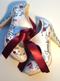 two white shoes with red ribbons tied around them