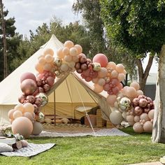 an arch made out of balloons in front of a tent