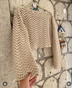 a hand holding onto a sweater hanging on a wall