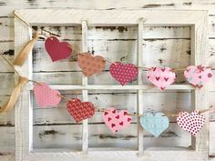 hearts are hung on a clothes line in an old window frame with burlocks