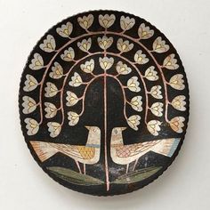 a black plate with two birds on it and hearts in the center, sitting on a white surface