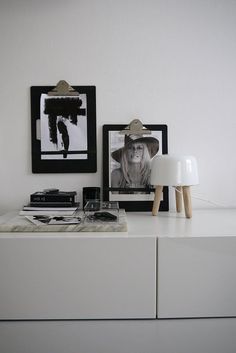 a white dresser with two pictures on it and a lamp next to the top shelf