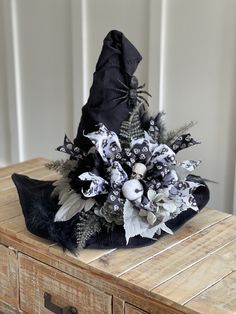 a black and white hat with feathers on top of a wooden table next to a dresser