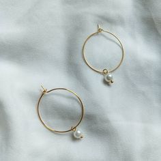 pair of gold hoop earrings with pearls on white fabric