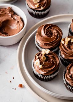 cupcakes with chocolate frosting and nuts on a plate