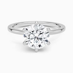 a round brilliant cut diamond ring on a plain white background, with the center setting in 18k white gold