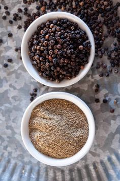 two white bowls filled with spices on top of a metal counter next to each other