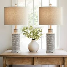 two lamps sitting on top of a table next to a vase with flowers in it