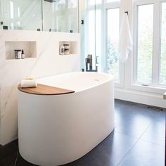 a large white bath tub sitting next to a window