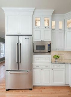 a large kitchen with white cabinets and stainless steel appliances, along with hardwood flooring