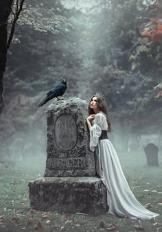 a woman standing next to a black bird on top of a stone statue in a graveyard