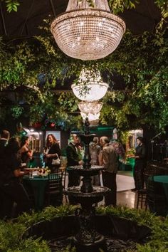 a group of people standing around a table under a chandelier