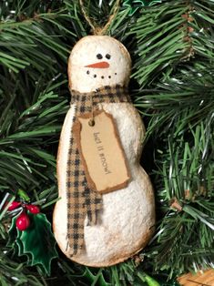 a snowman ornament hanging from a christmas tree with ornaments around it and a tag on the top