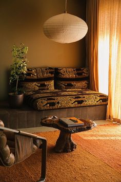 a bed sitting in a bedroom next to a table with a plant on it and a lamp hanging from the ceiling