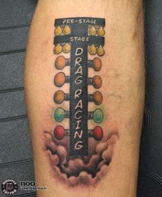 a man's leg with a tattoo on it that says drag racing in front of a street sign