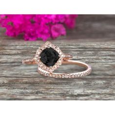 a black and white diamond ring on top of a wooden table with pink flowers in the background