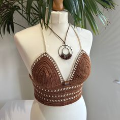 Handmade brown and beige Crochet Bralette Crop Top with adjustable tie back and glass bead embellishment. This top is made in a high quality beautiful brown yarn with beige details and features a fully adjustable halterneck tie, and a fully adjustable tie up back. It also features a bronze glass bead in the front center.  Due to its customisable nature, this top would fit someone between the sizes of UK 6/8 to UK14. Approximate cup size A - C. Displayed on a UK size 8/10 mannequin. Necklace not Beach Crochet Top In Brown, Brown Crochet Beach Top, Beach Brown Crochet Top, Brown Crochet Top For Beach, Festival Brown Crochet Lace Top, Bohemian Brown Crochet Top For Festival, Fitted Brown Halter Top For Festivals, Brown Triangle Halter Top, Top Cafe