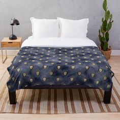 a bed with a blue and gold pattern on it next to a potted plant