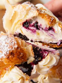 a pastry with blueberries and cream is cut in half