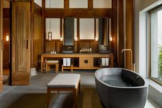 a large bathtub sitting next to a window in a room with wood paneling