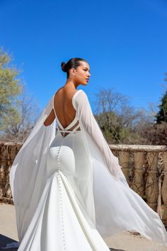 a woman in a white wedding dress is walking down the street with her back to the camera