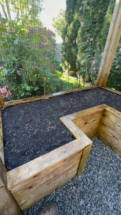 a wooden bench sitting in the middle of a garden area with gravel and plants around it