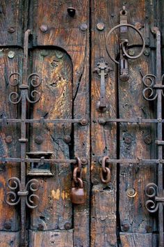 an old wooden door with iron bars and padlocks