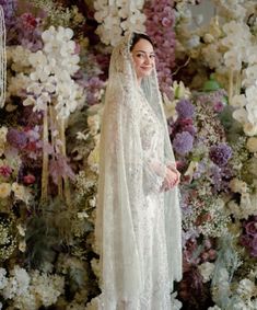 a woman standing in front of flowers wearing a veil