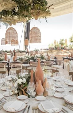 an outdoor dining area with tables, chairs and vases on the table set for dinner