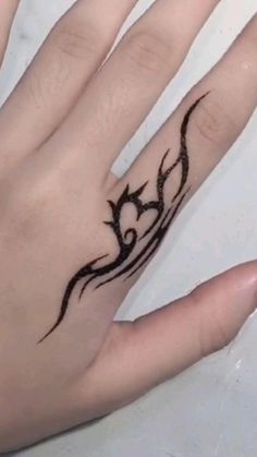 a woman's hand with a black tattoo on it and a ring in the middle