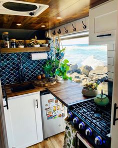 a kitchen area with an oven, stove and sink in front of the window looking out to the ocean